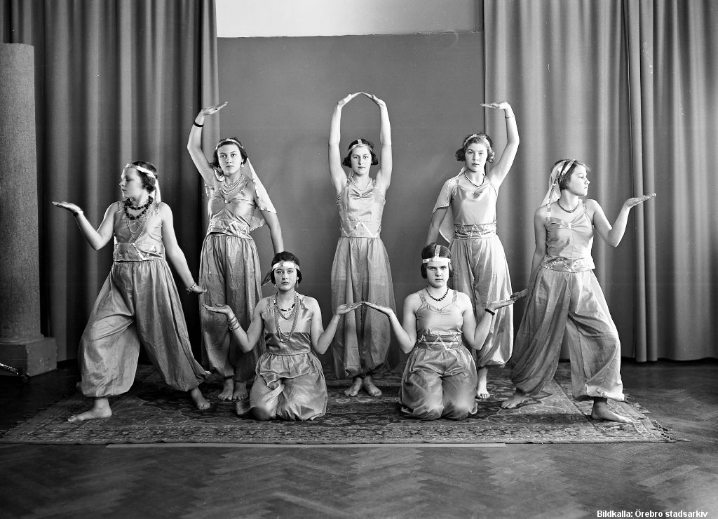 Sju unga kvinnor i dansanta poser.
