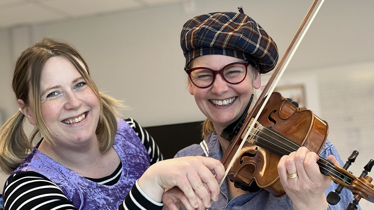 Två leende kvinnor som spelar instrument.