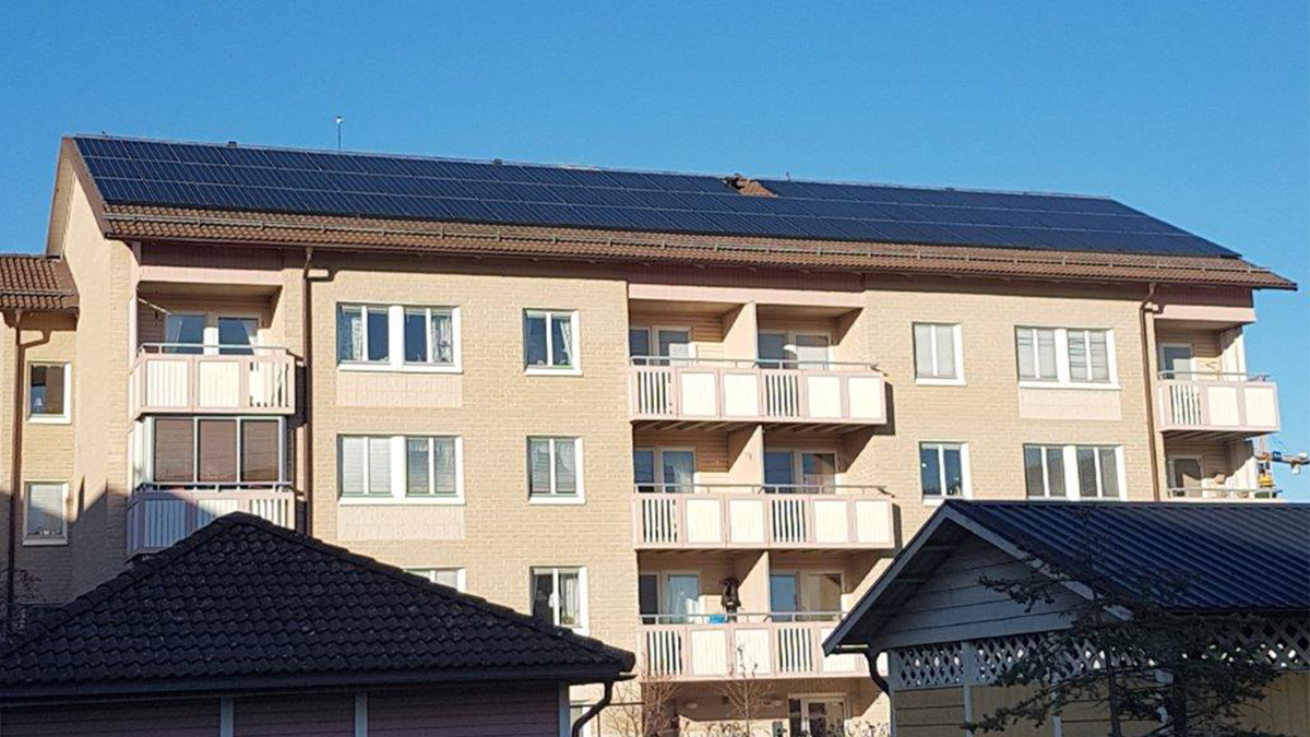 Solceller på hustaket på ett flerfamiljshus i tegel.