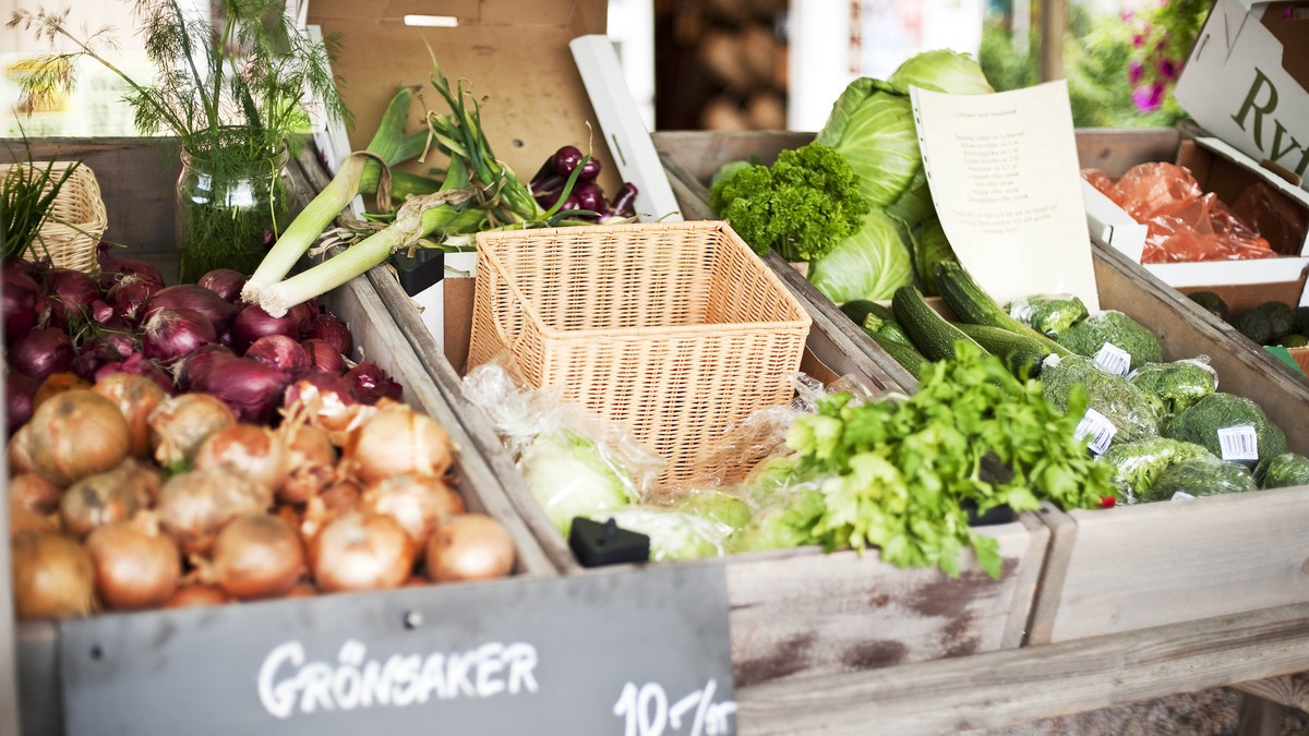 Marknadsstånd med olika sorters grönsaker som rödlök, gul lök, broccoli, dill, purjolök och vitkål.