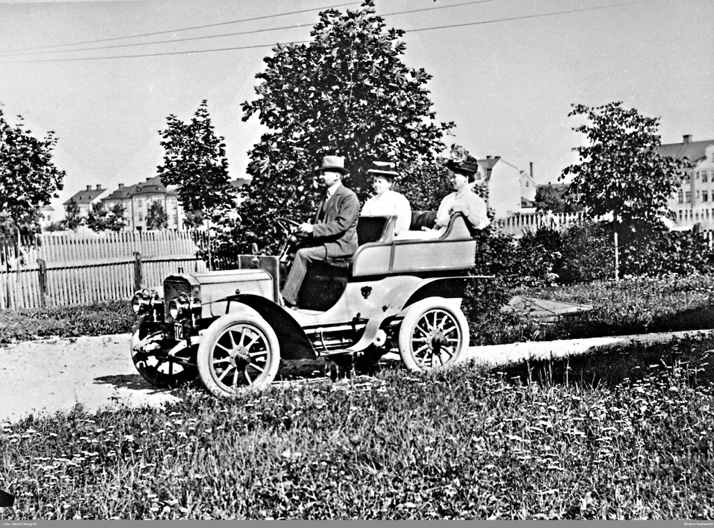 En man och två kvinnor i en bil av äldre modell