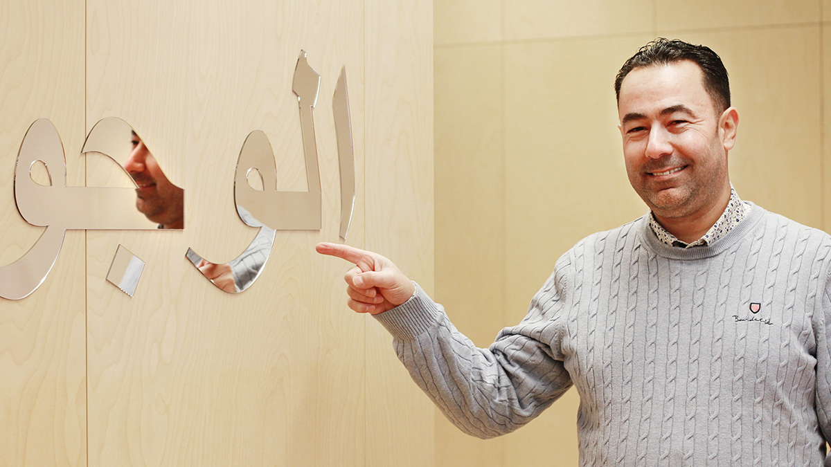 Man pekar på glaskonstverk med arabisk skrift.